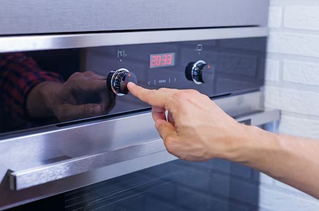 Melhor Forno elétrico moderno sobre a bancada, com assadeira dourando no interior e painel aceso.