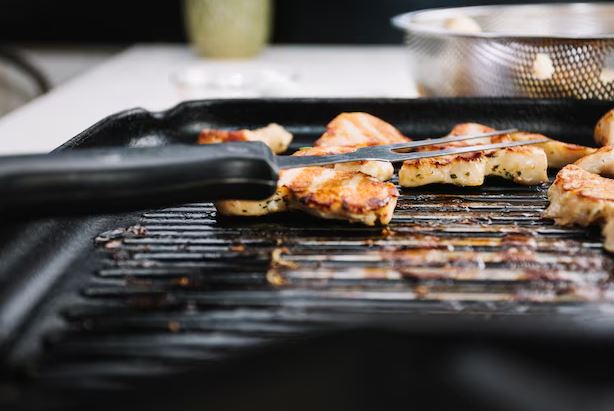 Melhor Grill elétrico aberto sobre bancada de cozinha, grelhando carnes e legumes com fumaça leve