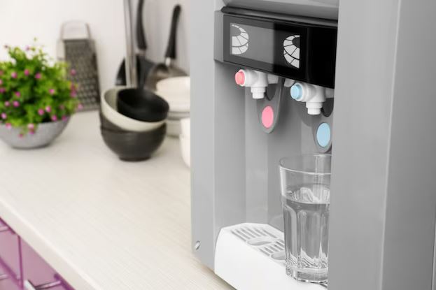 Melhor Purificador de Água Cozinha moderna com purificador de água instalado ao lado da pia, com copo de água cristalina sobre o balcão